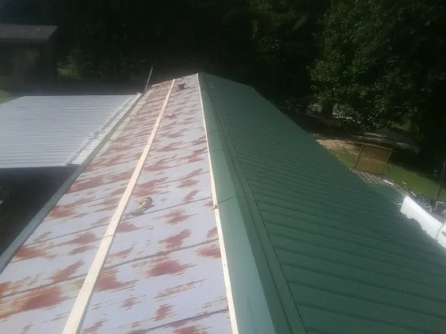 Old rusted panels beside newly installed green metal roofing — Wind Damage Roof Repair by Roofing Brothers in South Wellfleet