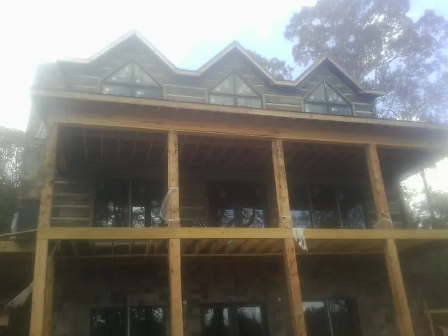 Dormers and porch framing on a large log home under construction — Roof Coating work by our crew in South Wellfleet
