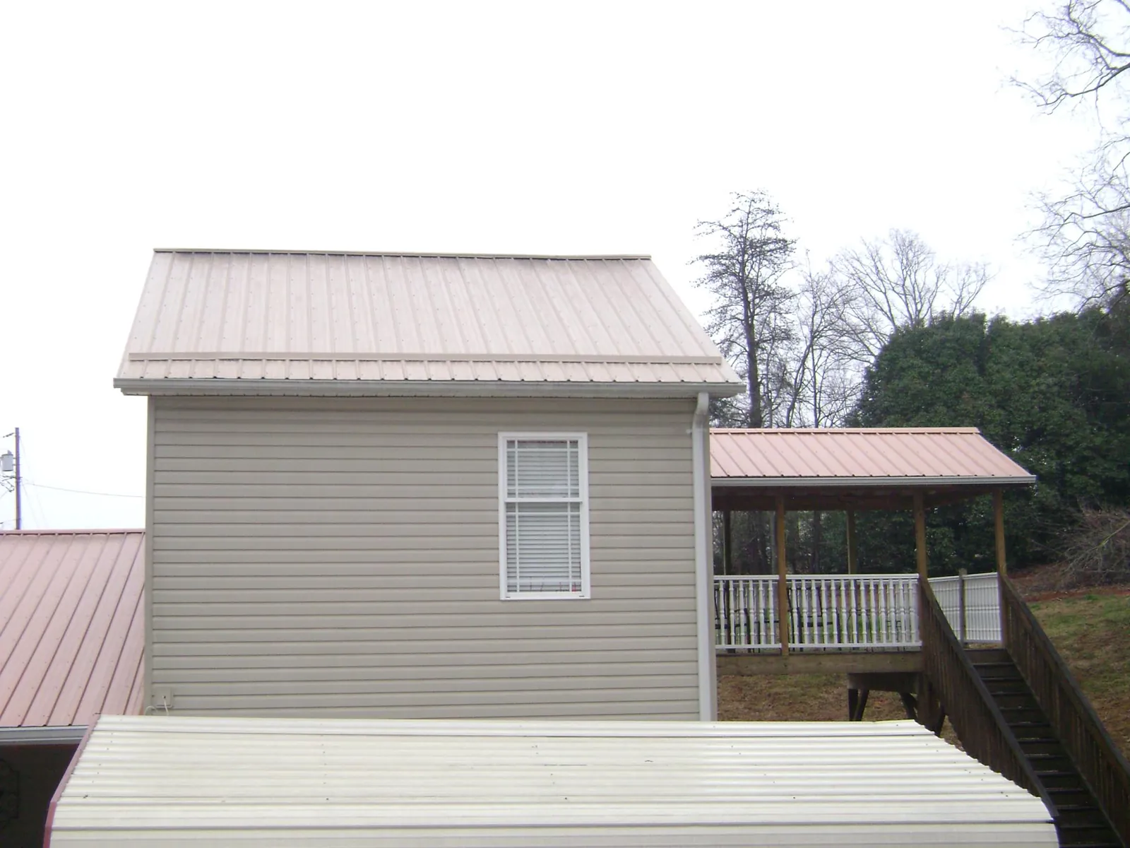 Tan metal roofs on a two story addition and attached porch, from a Roof Replacement job in South Wellfleet