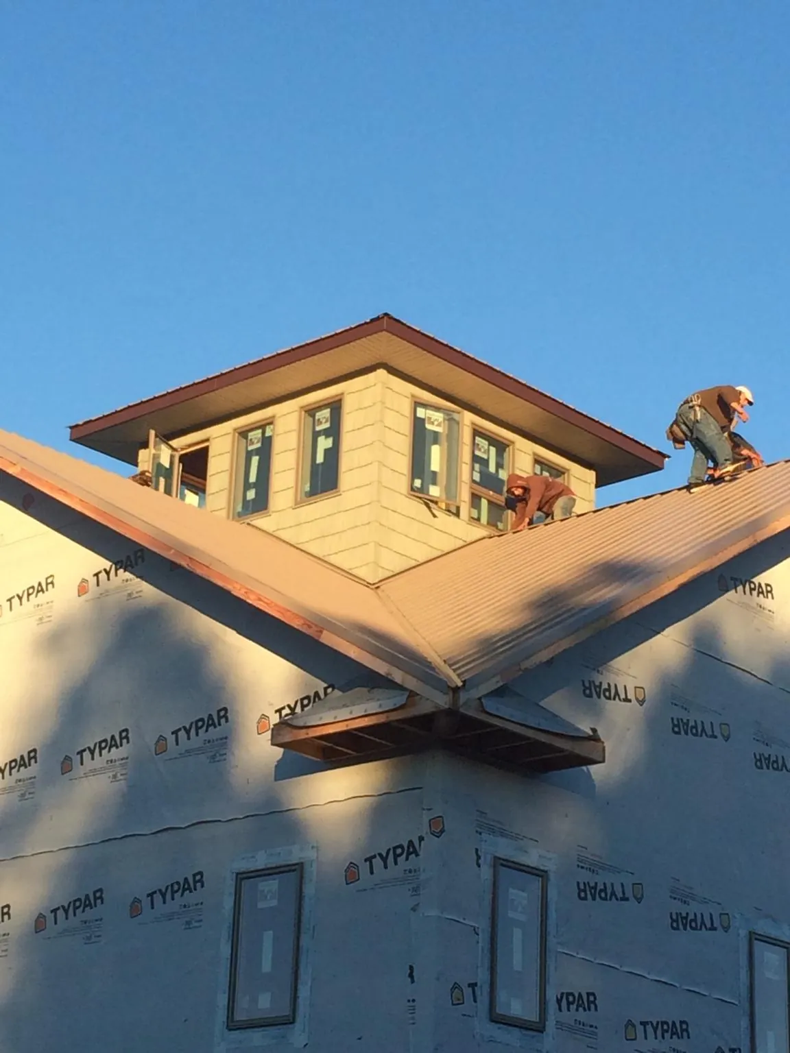 Roofers working around a rooftop cupola on a new metal roof at sunset — Roof Waterproofing in South Wellfleet by Roofing Brothers